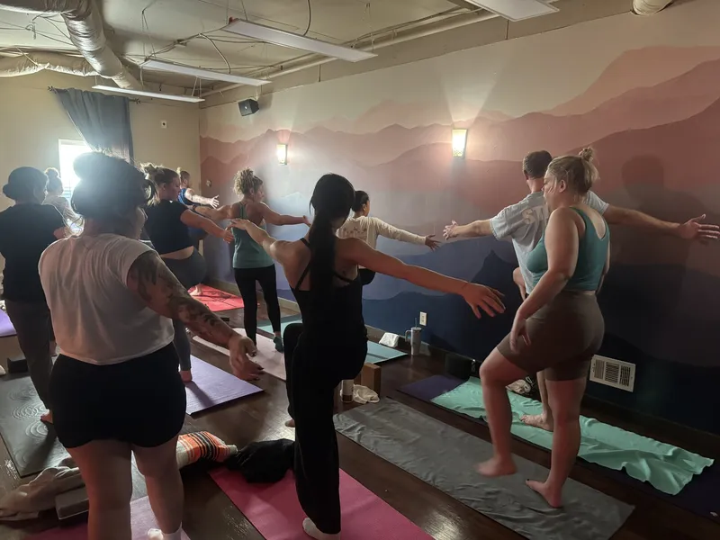 A class balancing on one leg with arms out wide in front of our mountain mural